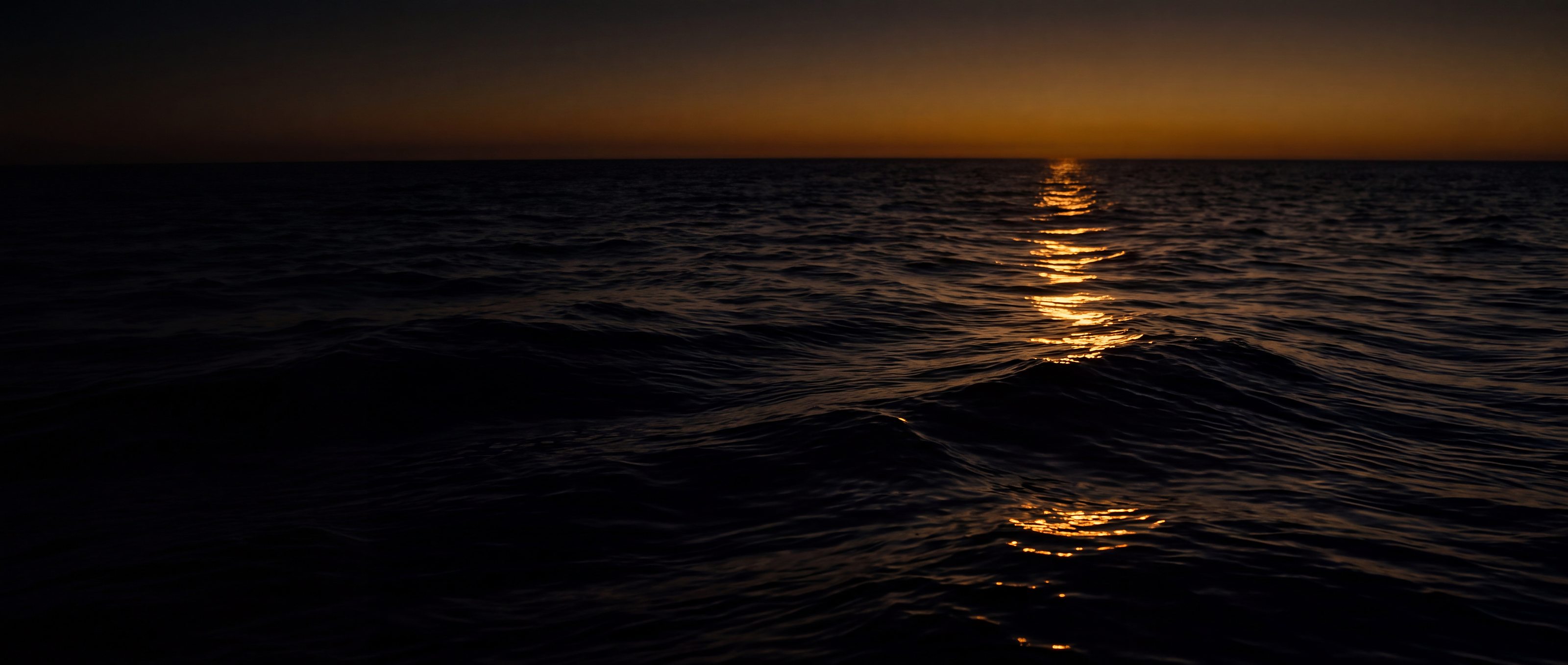 Mare nero al crepuscolo con una scia di riflesso dorato verso l'orizzonte