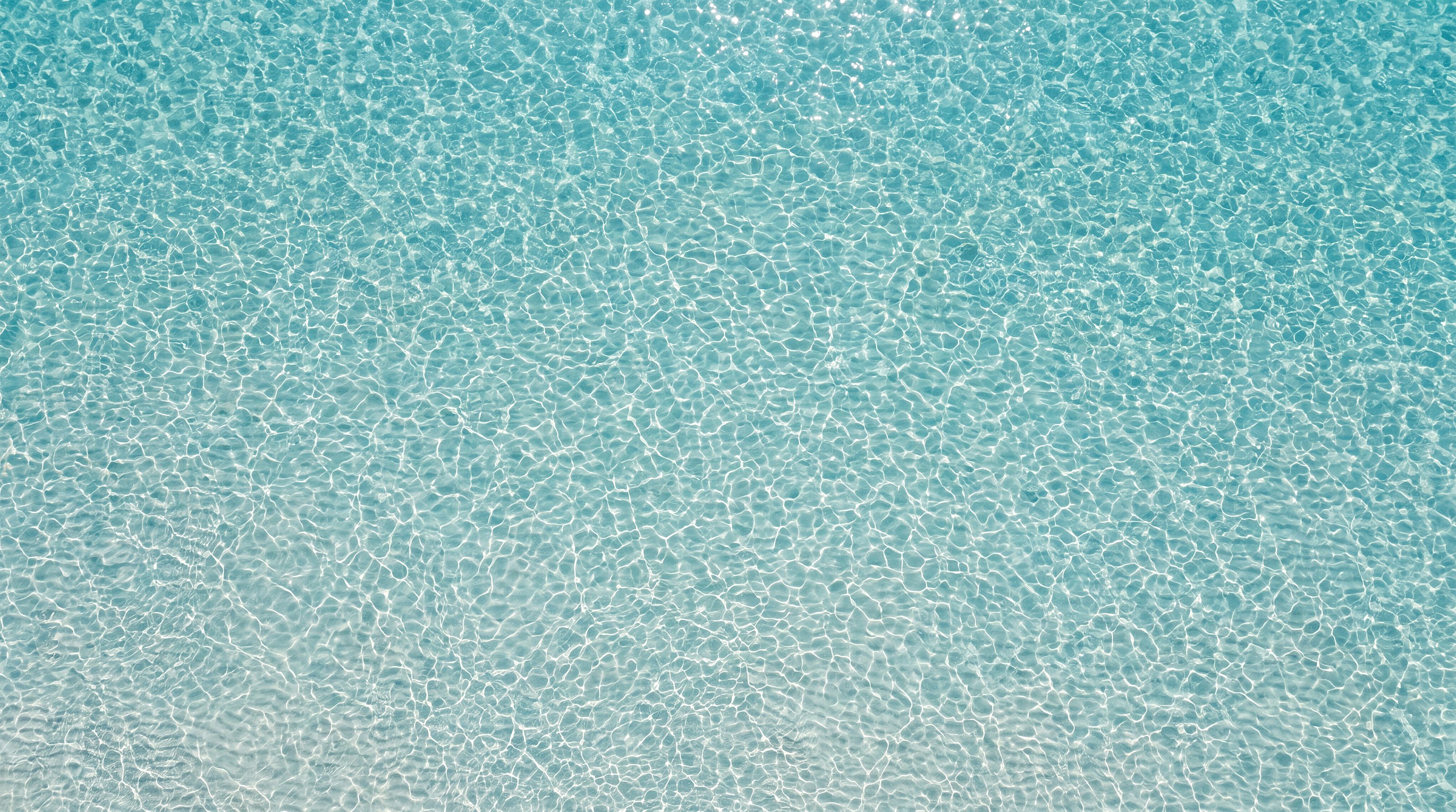 Visione Naviglia: il mare turchese visto dall'alto, acqua trasparente su sabbia chiara con i riflessi del sole