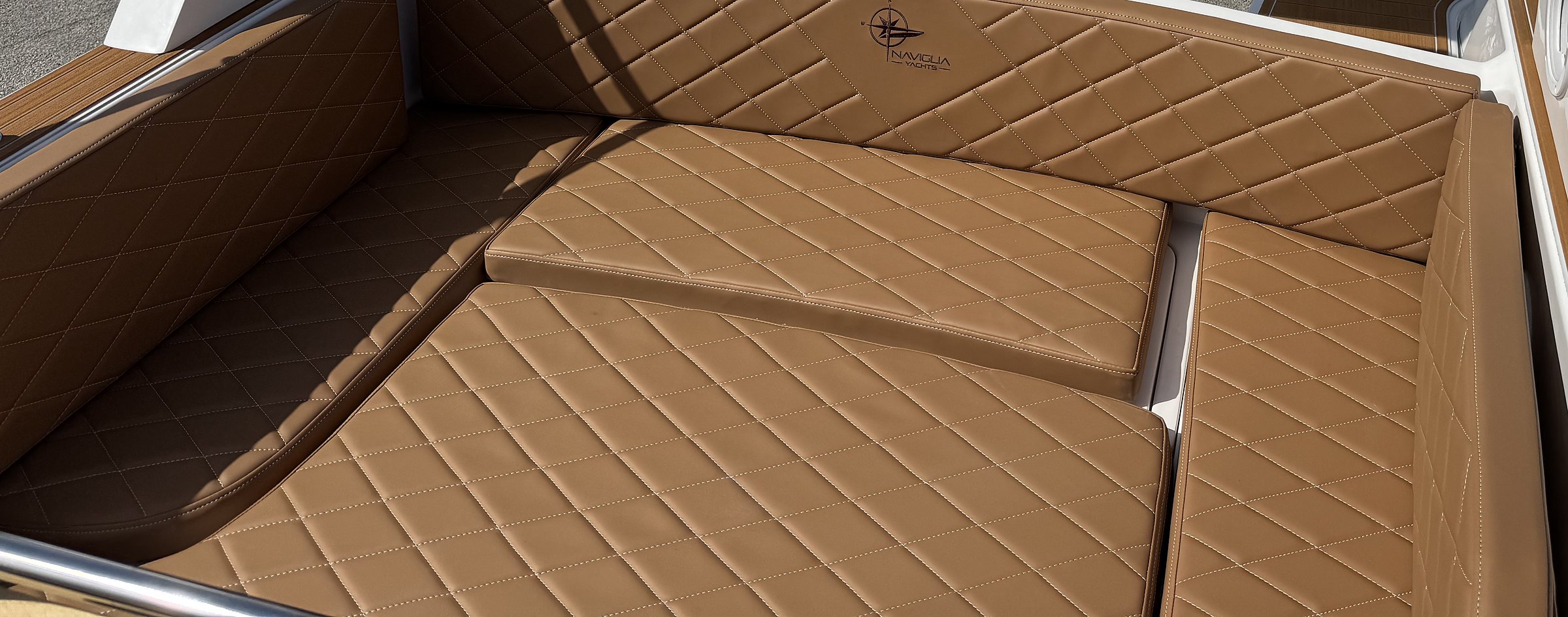 Tobacco U-shaped aft sofa, diamond-quilted, with Naviglia Yachts logo