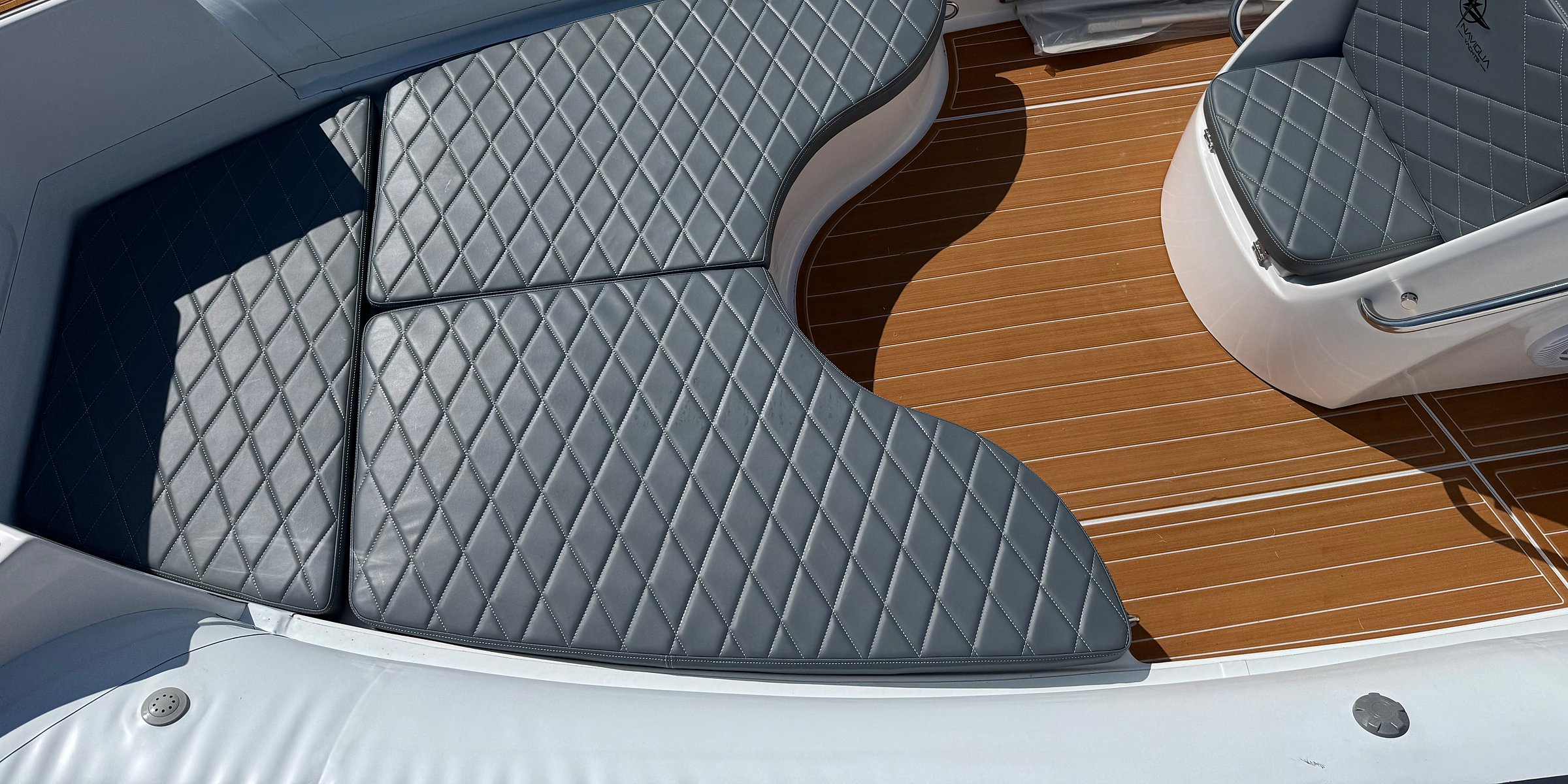 Grey diamond-quilted bow sun pad and teak-effect decking of the white NAVY 7.60