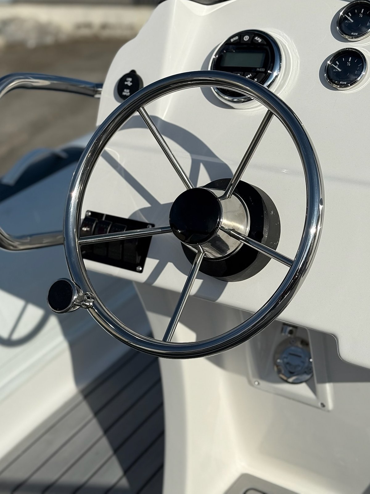 Spoked stainless steering wheel and gauges on the white console of the NAVY 6.00