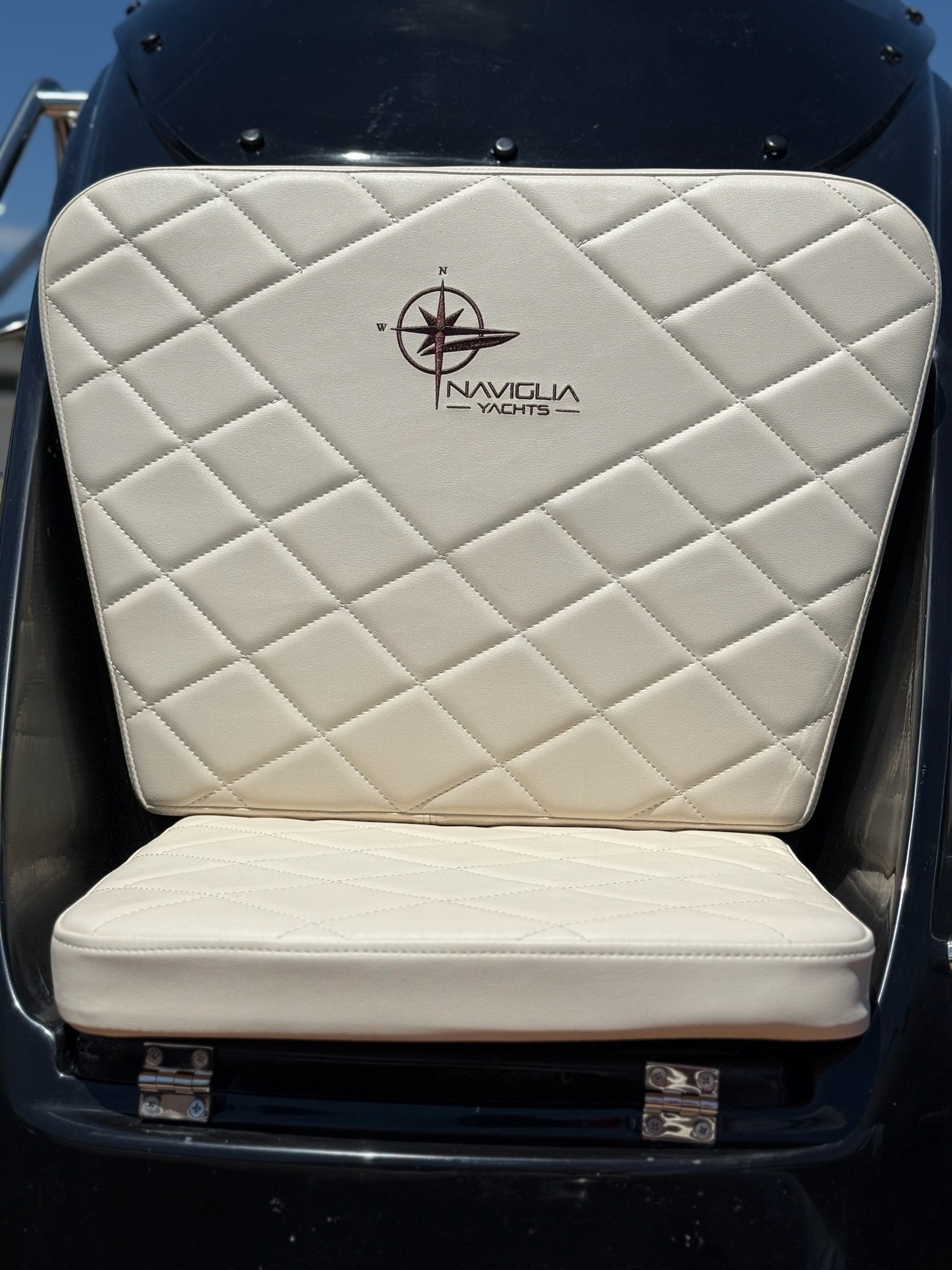 Seduta fronte consolle crema trapuntata con logo Naviglia Yachts su consolle nera lucida