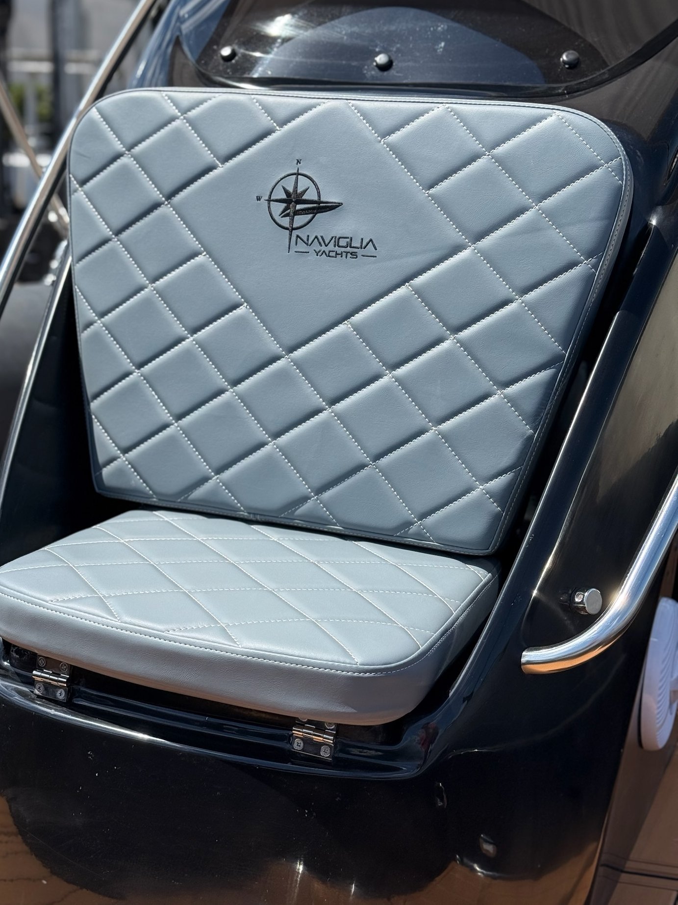 Seduta fronte consolle grigio chiaro trapuntata con logo Naviglia Yachts e tientibene inox