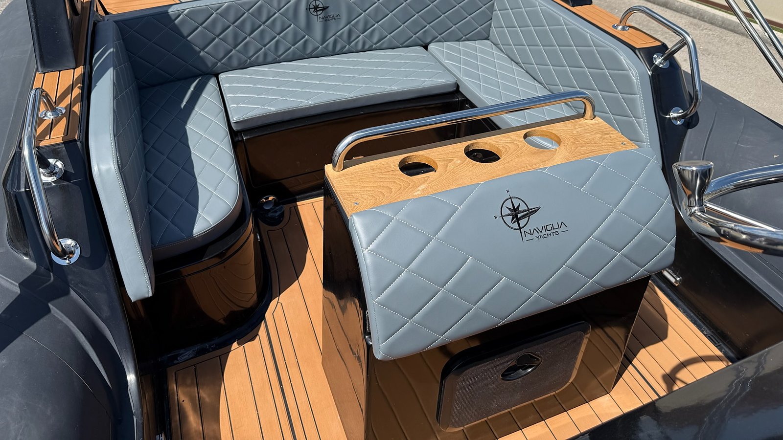 Dinette di poppa con cuscineria grigio chiaro, mobile con piano in legno e logo, NAVY 7.60