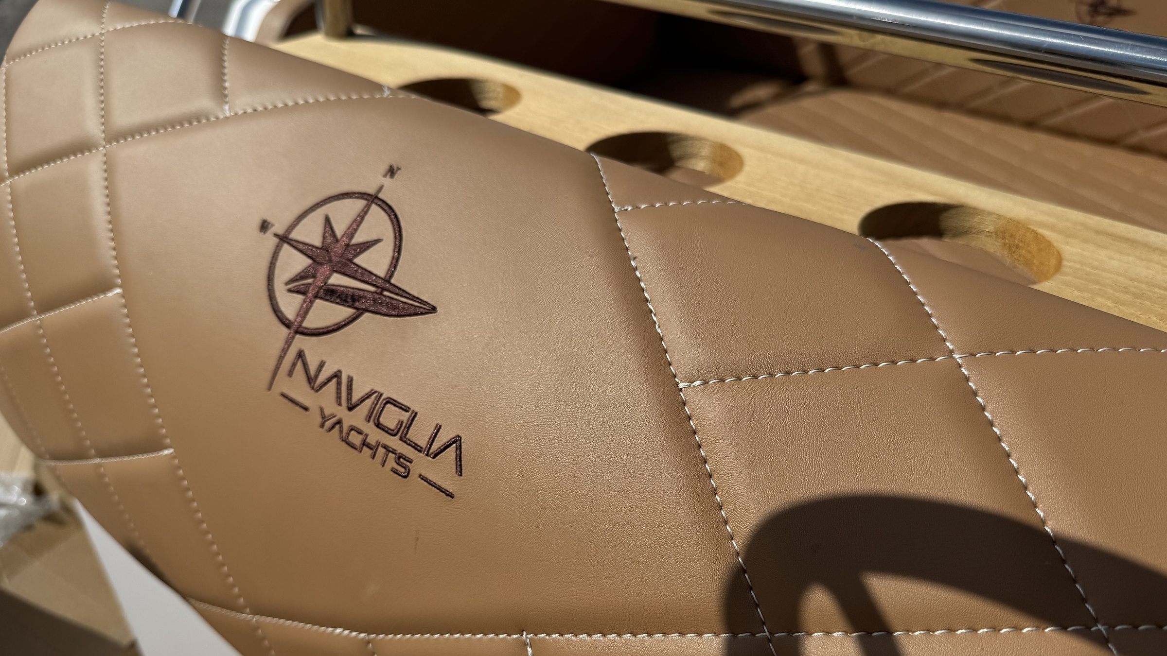 Naviglia Yachts logo stamped on quilted tobacco upholstery, with teak cup holders