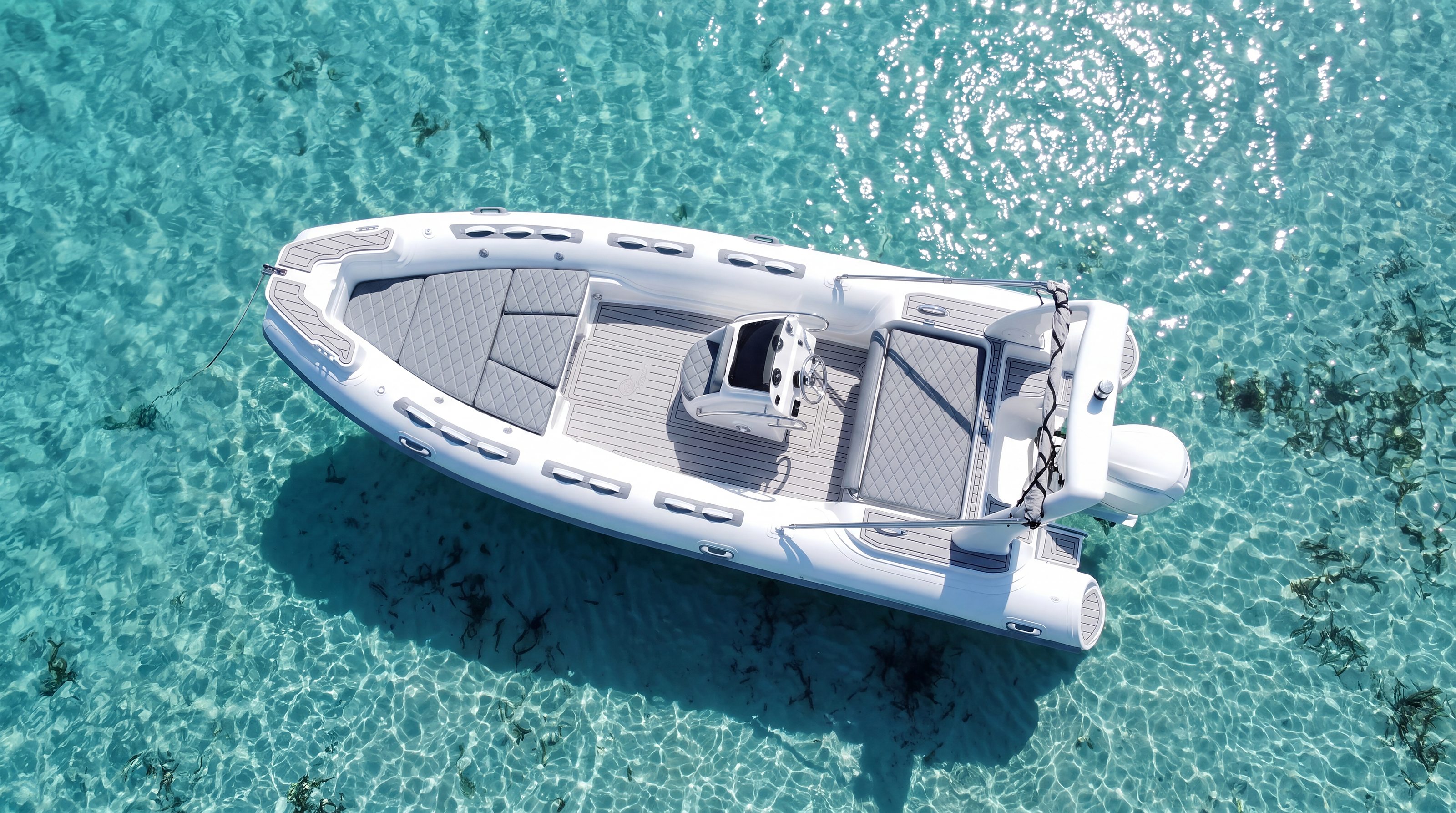 Naviglia vision: the white NAVY 6.00 seen from above at anchor on turquoise water, grey sunpad and teak-effect deck