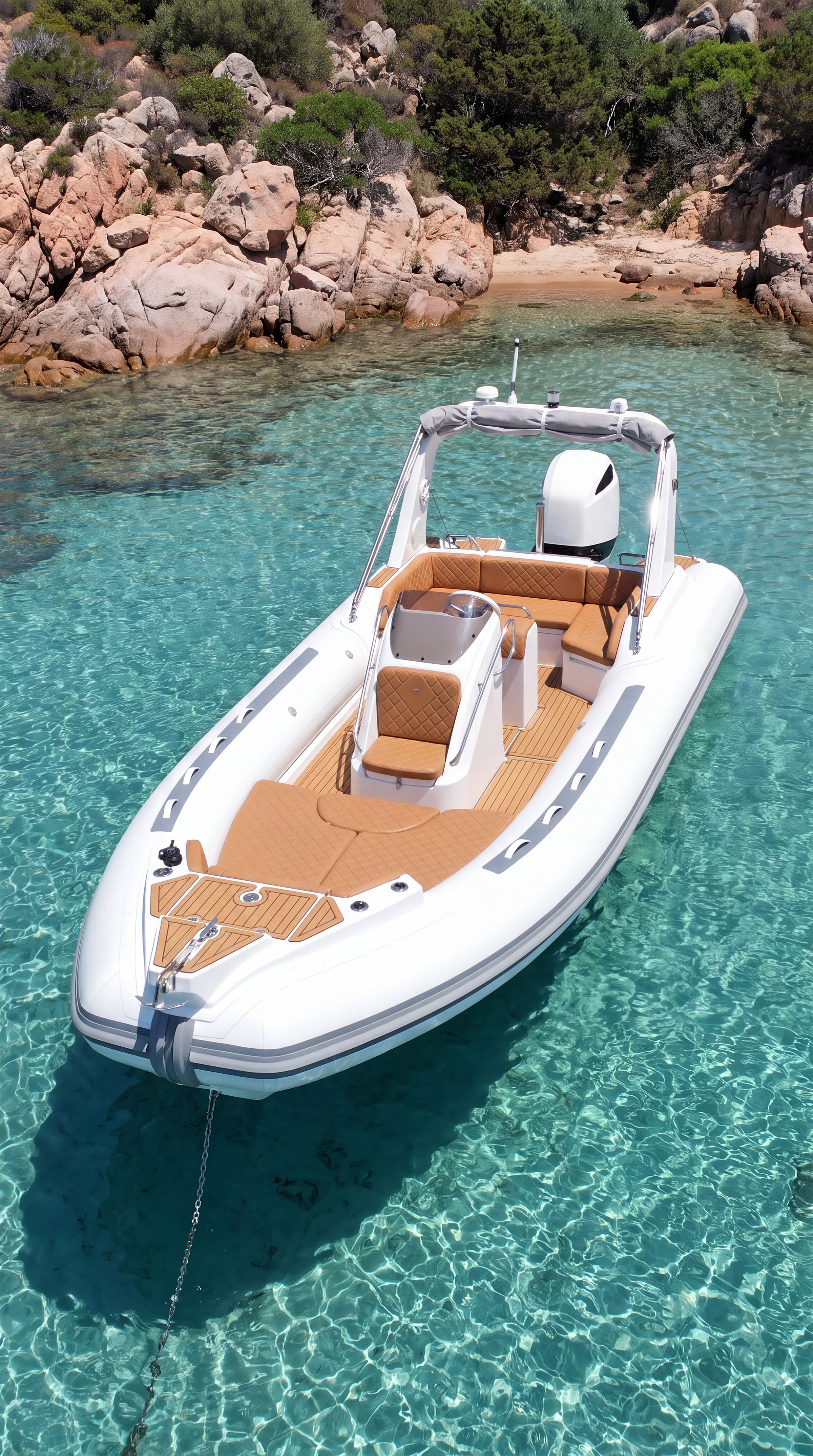 Naviglia vision: the white NAVY 7.60 at anchor in a small pink granite cove, on clear turquoise water, seen from above