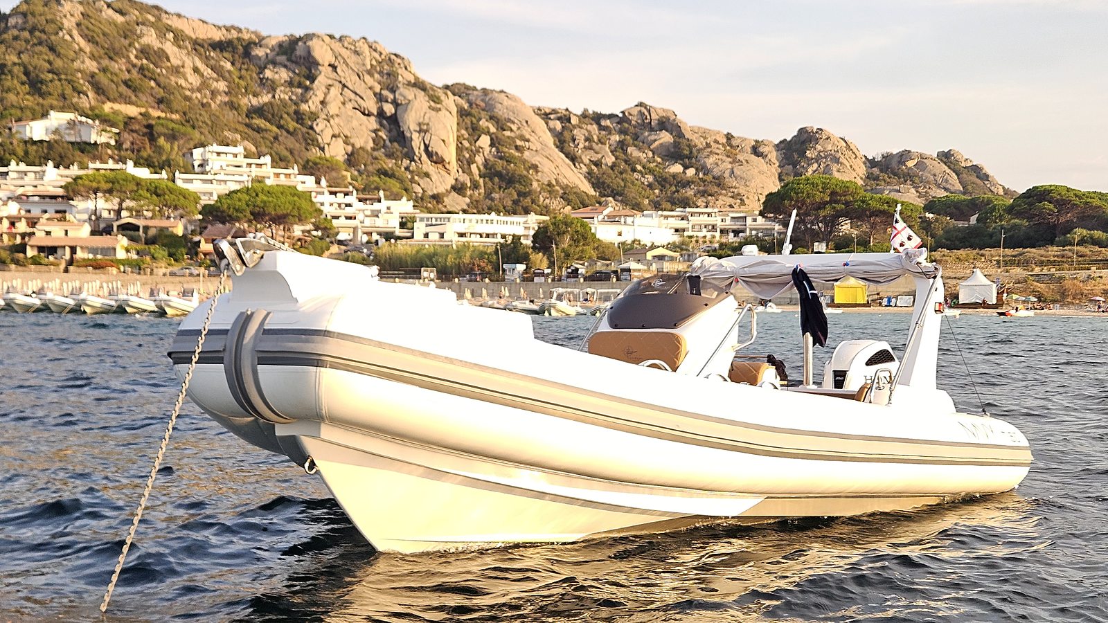 NAVY 7.60 bianco all'ancora nell'ora dorata, riflessi caldi sull'acqua e costa di granito