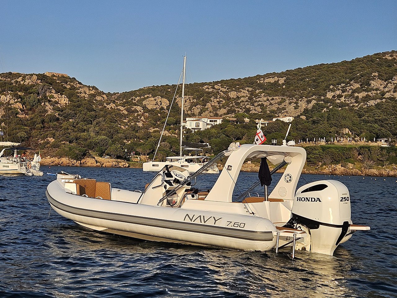 Full NAVY 7.60, stern three-quarter view, with Honda 250 outboard and green hillside
