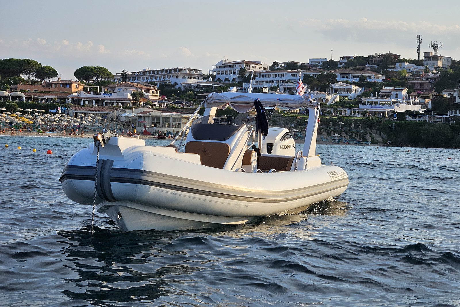 NAVY 7.60 at anchor, bow three-quarter view, tan upholstery and Honda outboard visible