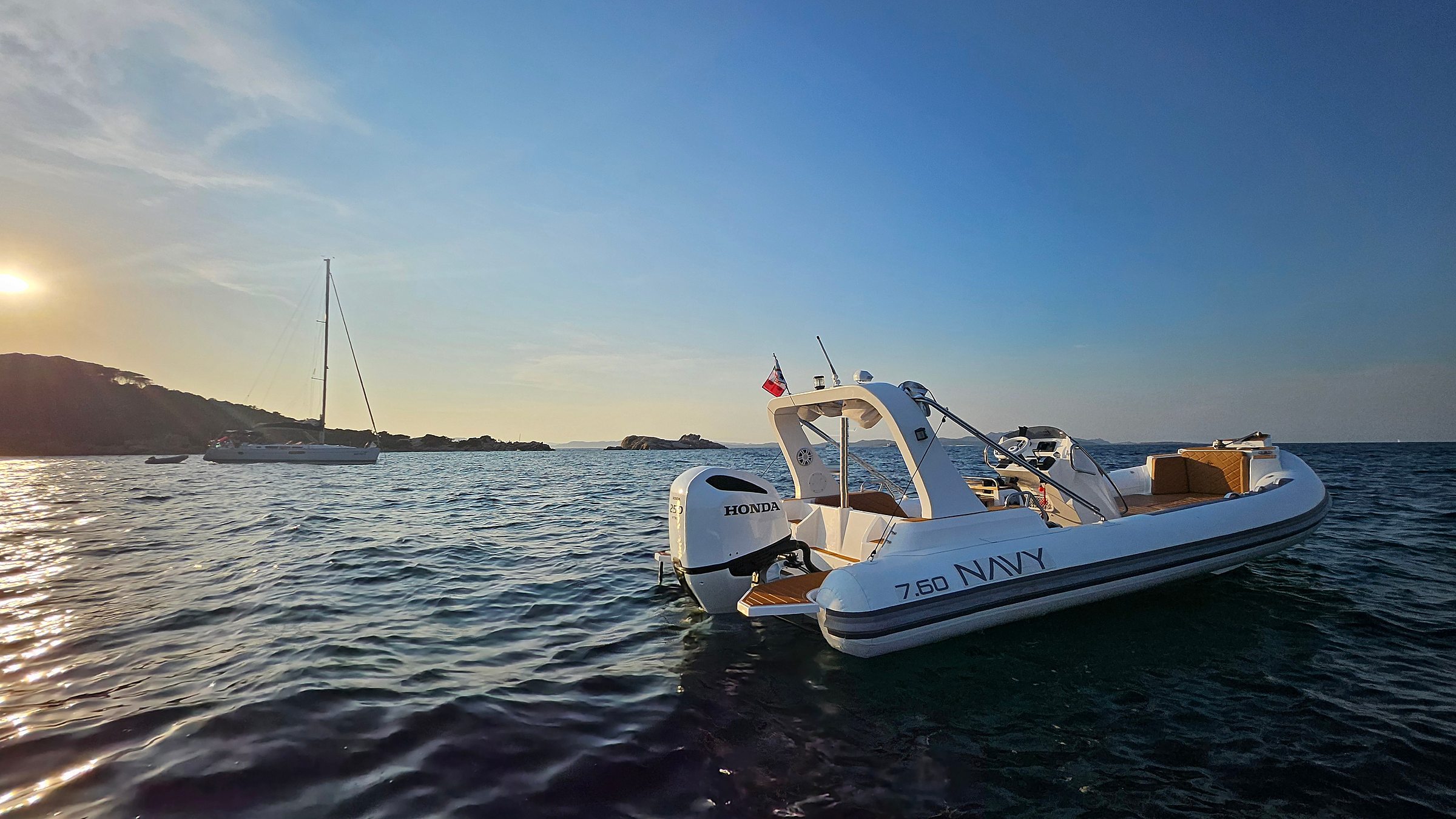 NAVY 7.60 bianco all'ancora al tramonto, fuoribordo Honda a poppa e sole basso sull'acqua