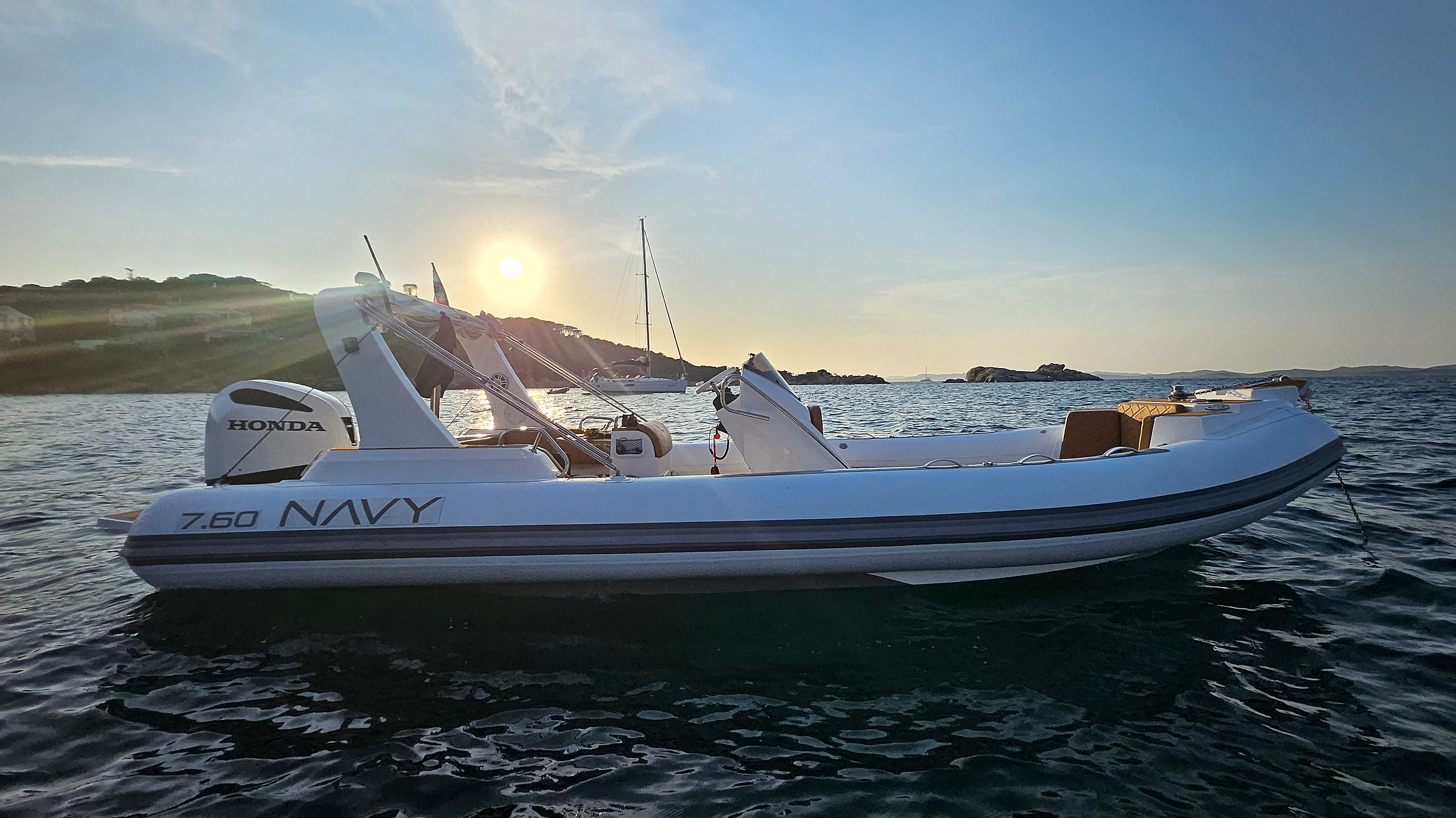Backlit profile of the NAVY 7.60, sunburst behind the roll bar, Honda outboard astern