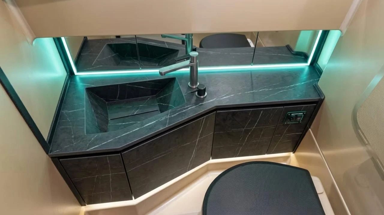 Naviglia vision: the separate heads of the new NAVY 9.50 Cabin seen from above, with the veined black counter and the basin carved from the same block, dark taps and the mirror framed in turquoise light