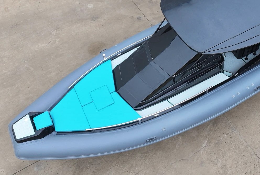 Photograph from the yard, detail: the bow of the NAVY 9.50 Cabin seen from above, with the turquoise sunpad and the gloss black coachroof